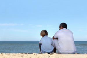 Father and son sitting on the edge of the ocean