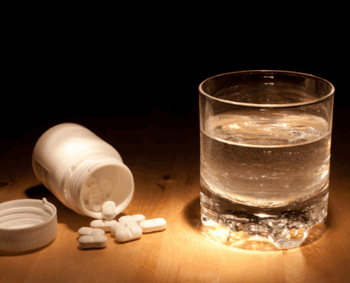 Prescription pills and a glass of water, representing chemical control and non-consensual drugging in marriage.