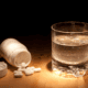 Prescription pills and a glass of water, representing chemical control and non-consensual drugging in marriage.